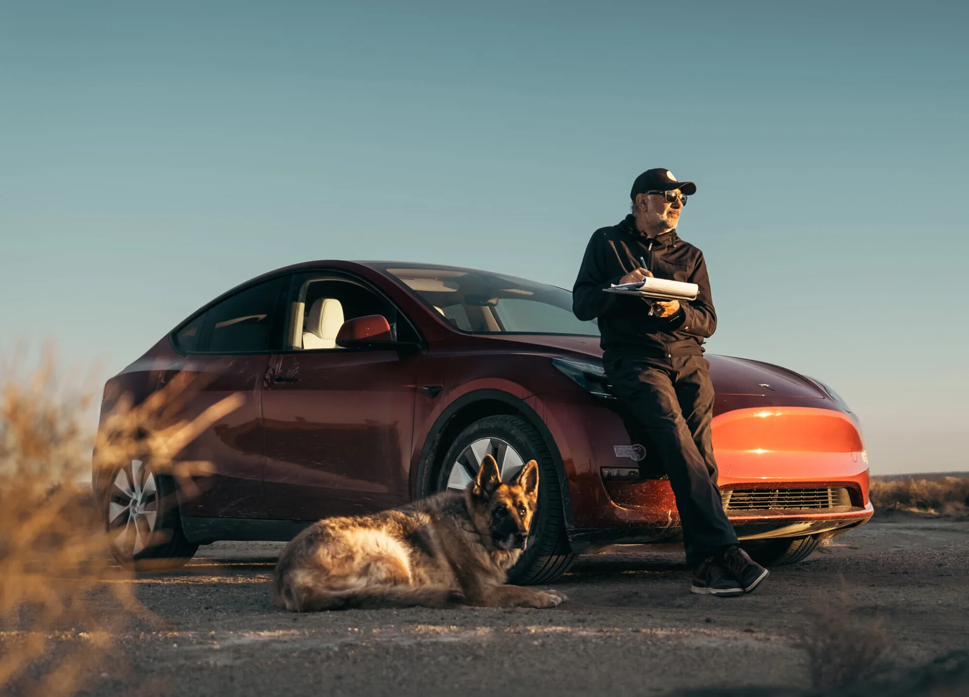 Azhar Hameed writing notes beside his car with his dog resting nearby